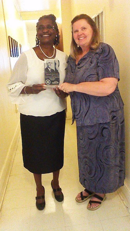 photo of Bishop Johnson holding the Hasenstab Award, a clear plaque