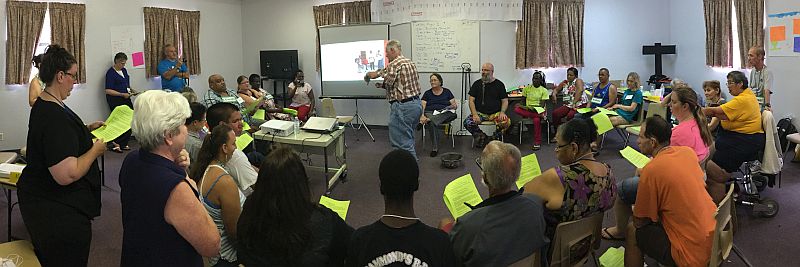 panorama photo of group in a circle, in the center a man is sharing.