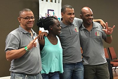 three men and one woman stand together, signing