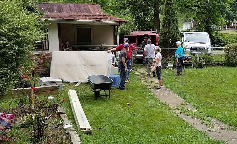 a group works on a yard and sidewalk