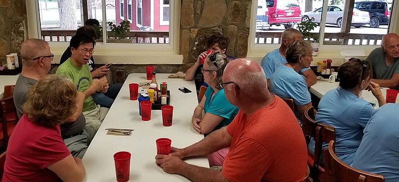 people gather around a table, ready to eat