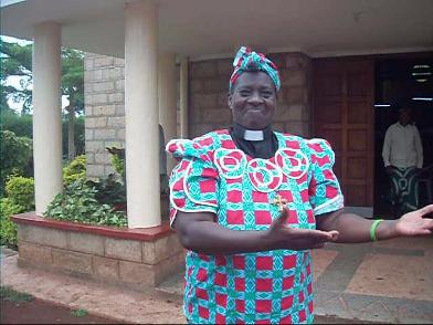 photograph of Margaret Mukami, with arms in a welcoming gesture.