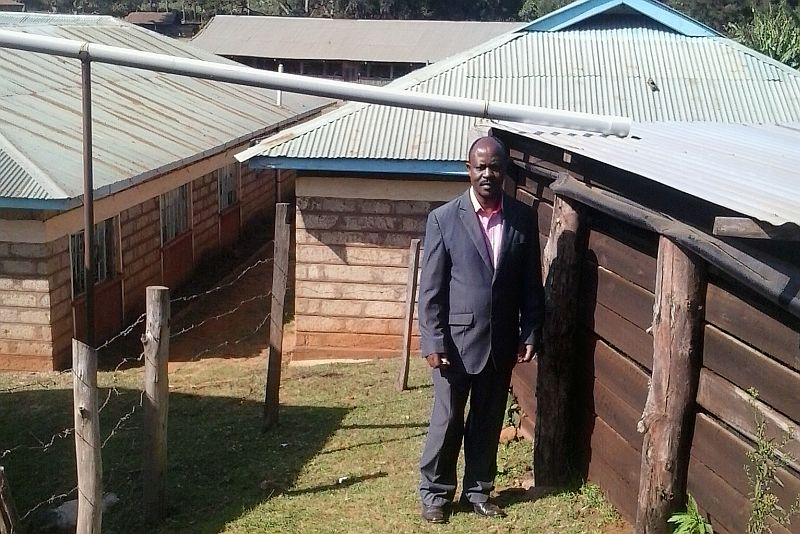 a person stands next to a well, and buildings surround it.