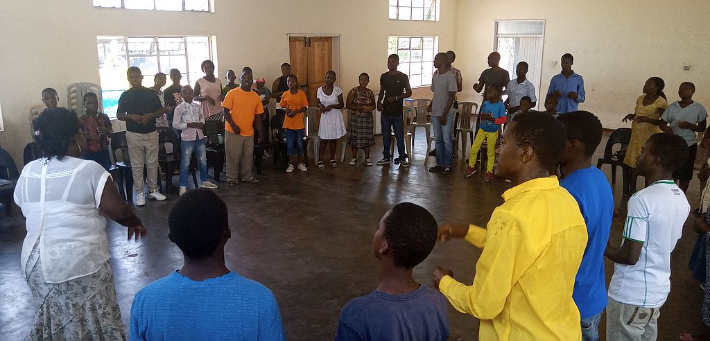 a large standing group in a circle, signing to each other.