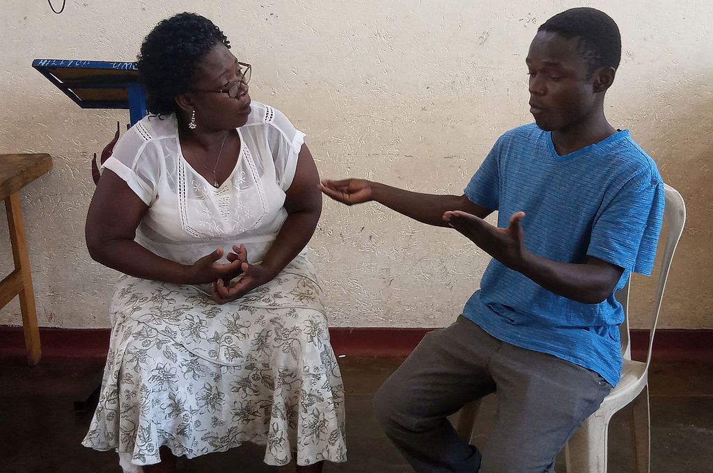 a man and a woman sit next to each other, signing.